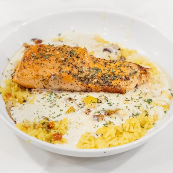 The Chalk Bar's salmon dish with yellow rice and creamy sauce, garnished with herbs.
